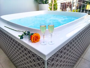 A hot tub with two glasses of champagne and a rose on a tiled platform. - Hotel Darsena (Riccione)