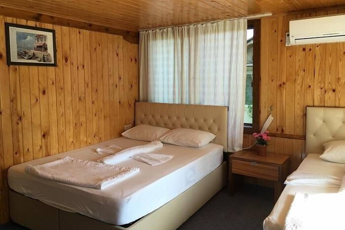 A wooden-paneled room with a bed, a bedside table, and a picture on the wall.