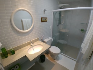 Une salle de bain moderne avec un lavabo blanc, un miroir, des toilettes et une douche à parois de verre.