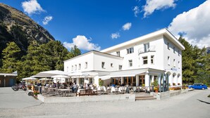 A white building with outdoor seating and a mountain backdrop. - Hotel Morteratsch (Pontresina)