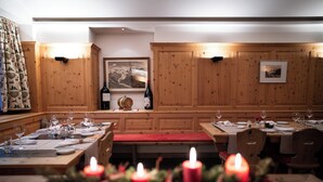 A restaurant with wooden panel walls, a wooden bench, and tables set for dining. - Hotel Morteratsch (Pontresina)