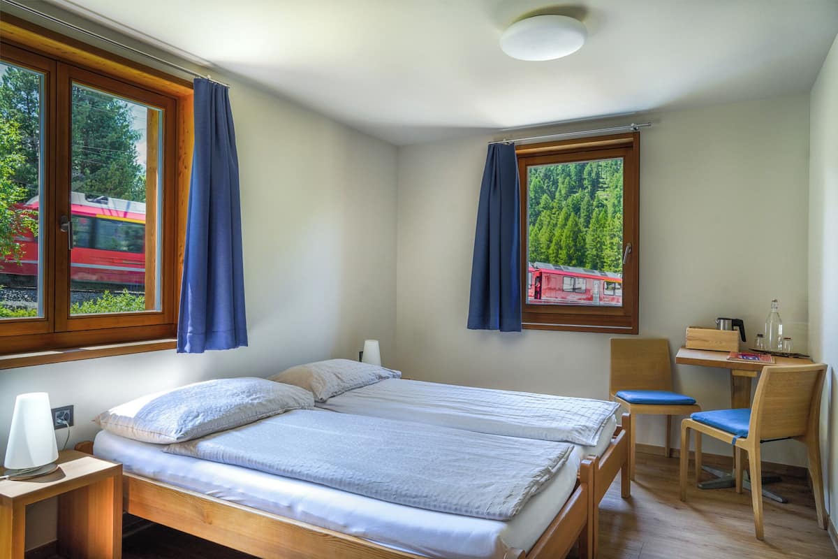 A bedroom with two beds, a desk, and a chair.