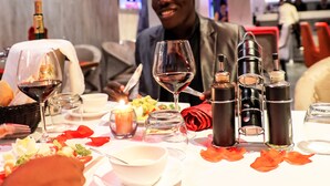 A dining table set with wine glasses, a bottle of wine, and a candle. - Hotel M'Rode (Lomé)
