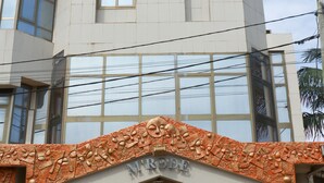 A building with a modern facade, large windows, and a prominent entrance with two large vases. - Hotel M'Rode (Lomé)