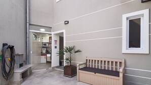 A clean, modern outdoor area with a wooden bench, a potted plant, and a hose on the left. - Villa Sophia (São Paulo)
