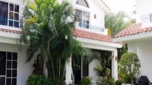 A two-story house with a covered patio, surrounded by lush greenery and a well-maintained lawn. - Casa en Marina Cid (Mazatlán)