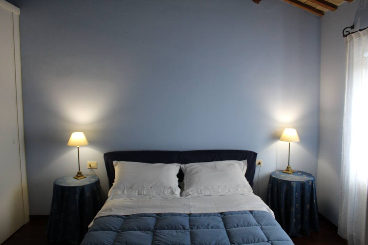 Une chambre à coucher avec un lit, deux tables de chevet et des lampes.