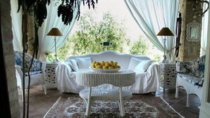 A cozy room with a white sofa, wicker side tables, and a patterned rug. - Villa Rondanella (Fermo)