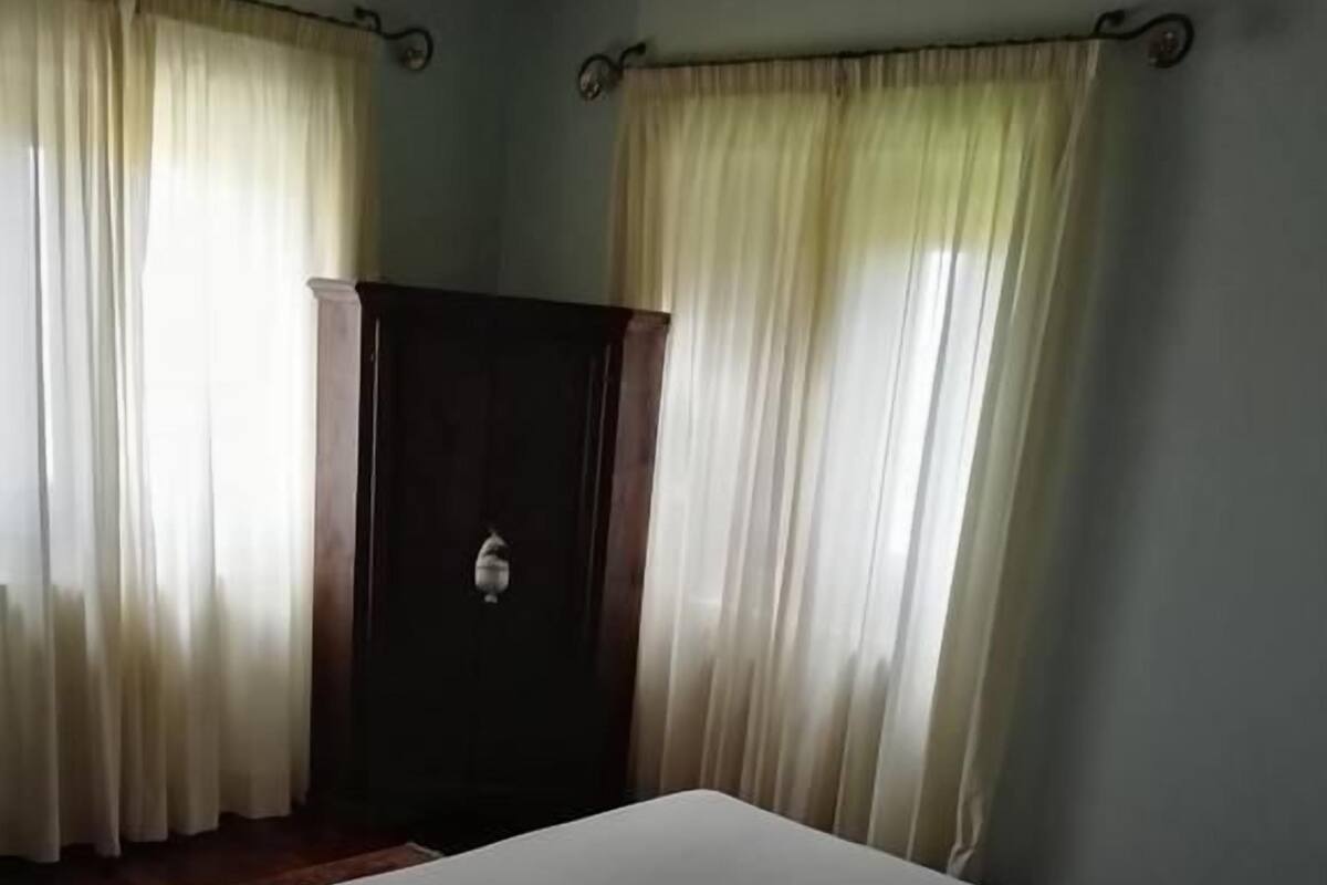 Une chambre avec un lit, une armoire et des rideaux.