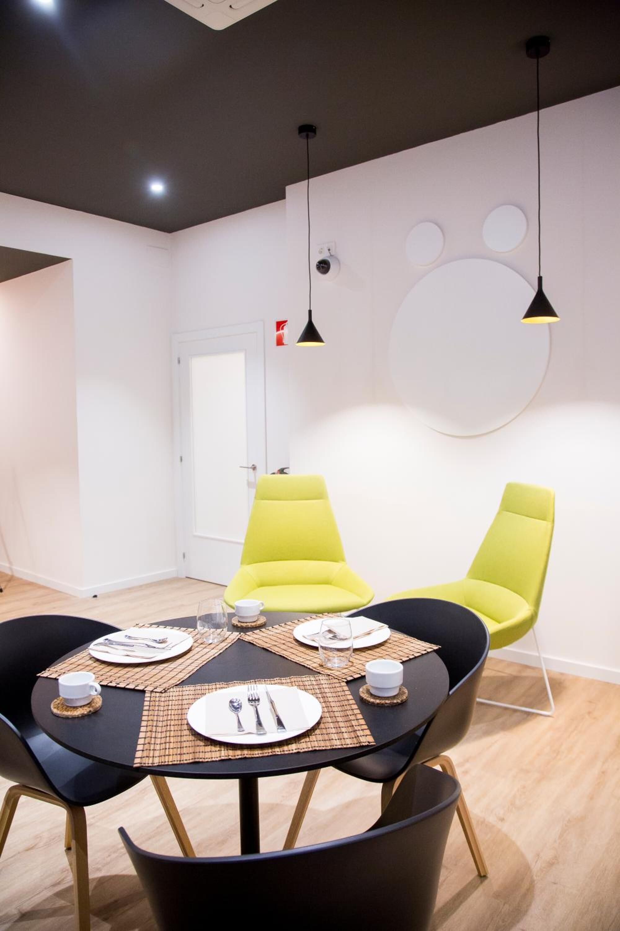 Een eetgedeelte met een ronde tafel voor vier personen, zwarte stoelen en gele stoelen.