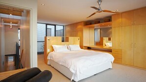 A modern bedroom with a large bed, wooden cabinets, and a ceiling fan. - 46 Loader De Waterkant (Cape Town)