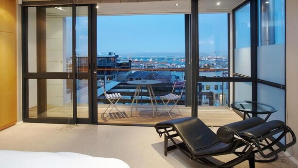 A modern hotel room with a large sliding glass door leading to a balcony with a city view. - 46 Loader De Waterkant (Cape Town)