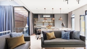 Ein modernes Wohnzimmer mit einem grauen Sofa, gemusterten Kissen und einem Holztisch.