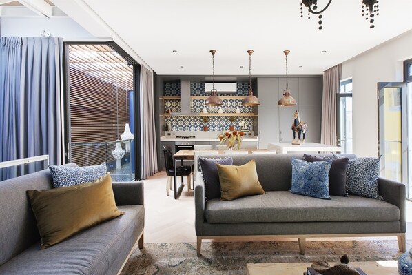 A modern living room with a grey sofa, patterned cushions, and a wooden coffee table.