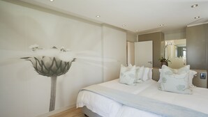Een slaapkamer met een groot bed, een spiegel aan de muur en een houten vloer.