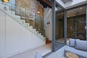 Een modern interieur met een trap, een glazen deur naar een buitenruimte en een zithoek met kussens.