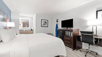 Een hotelkamer met een groot bed, een bureau met een computer, een televisie en een magnetron.