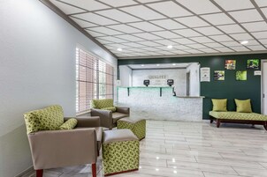 Un área de recepción con mostrador de registro, paredes verdes y suelo de baldosas.
