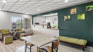 Un espace de détente moderne avec un sol en marbre, une longue table et plusieurs options de sièges confortables.