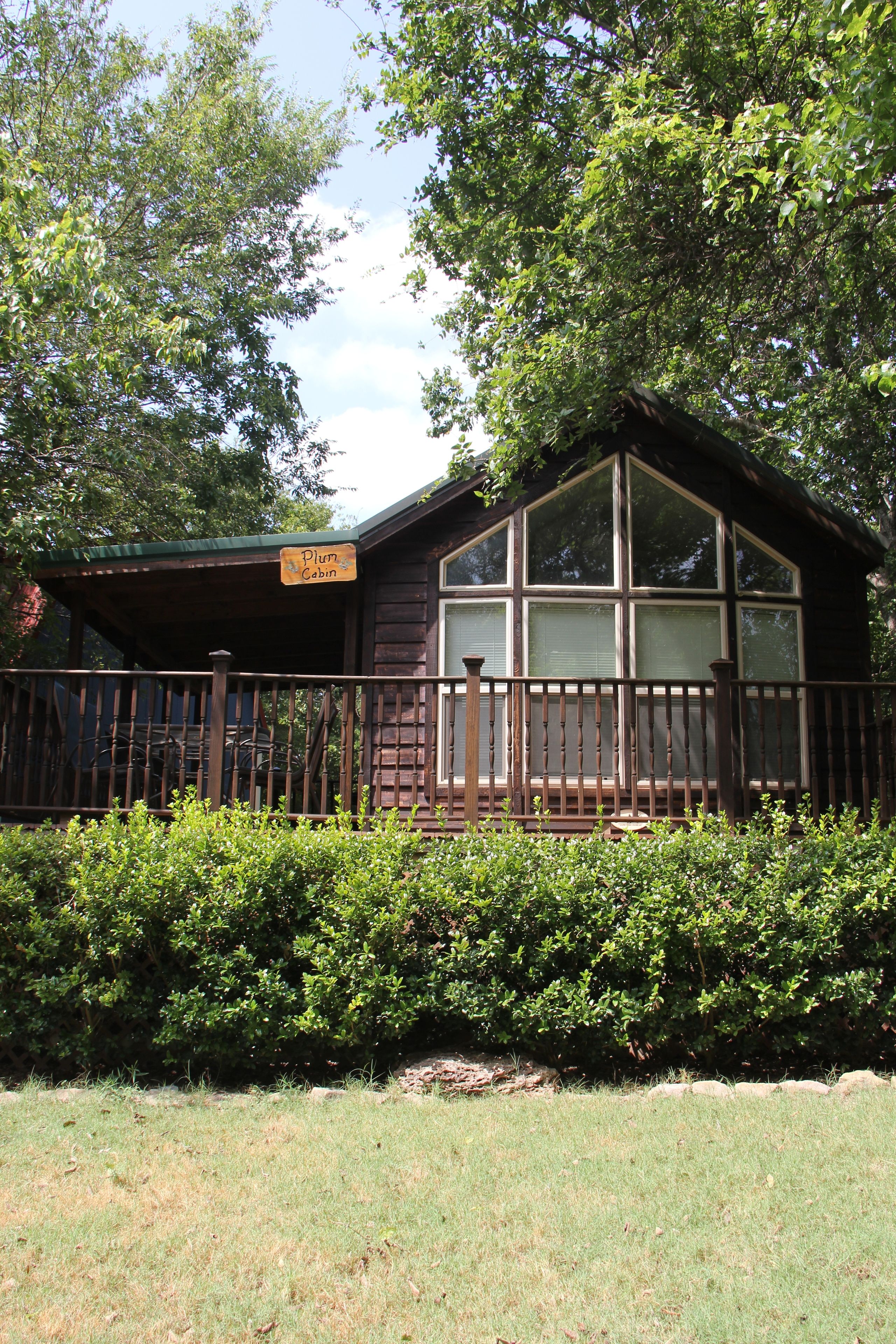 A cabin with a wooden exterior, large windows, and a sign indicating it is a "Pluto Cabin."