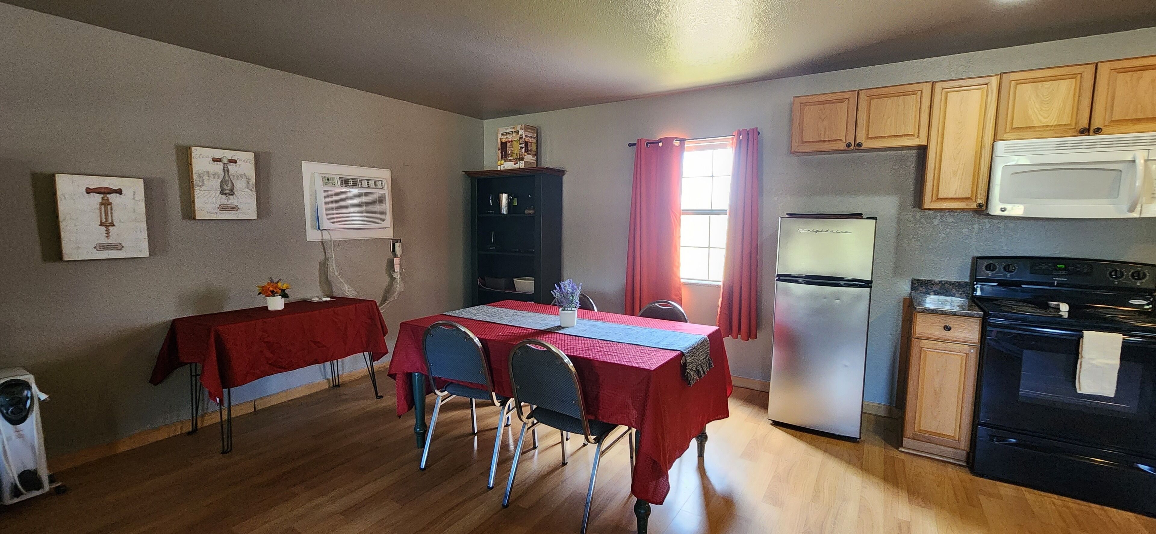 A compact kitchen with a dining area, wooden cabinets, a refrigerator, and a microwave.