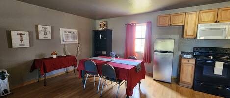 A compact kitchen with a dining area, wooden cabinets, a refrigerator, and a microwave.
