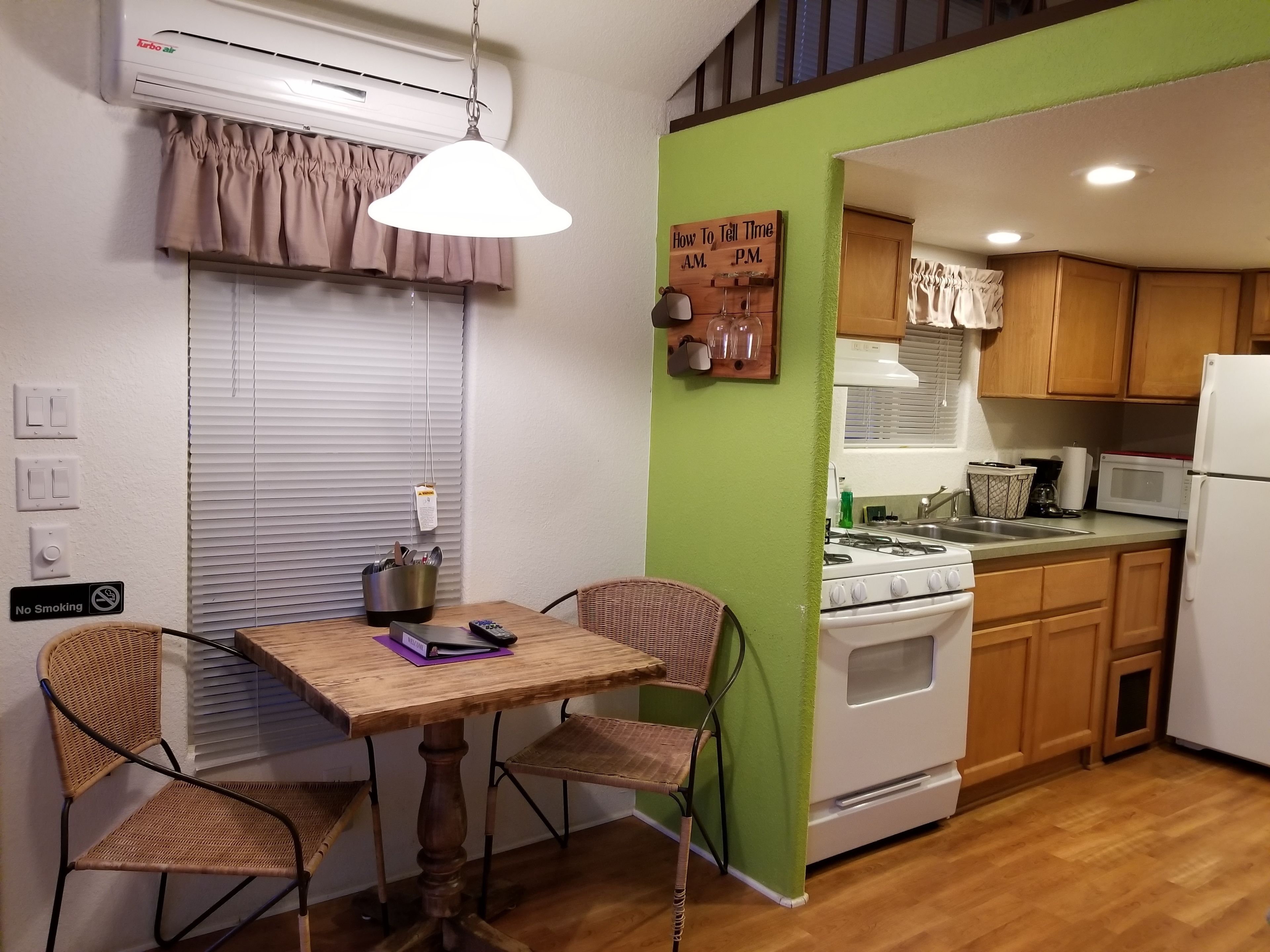 Cocina compacta con comedor, que incluye una mesa con sillas, estufa, microondas y refrigerador.
