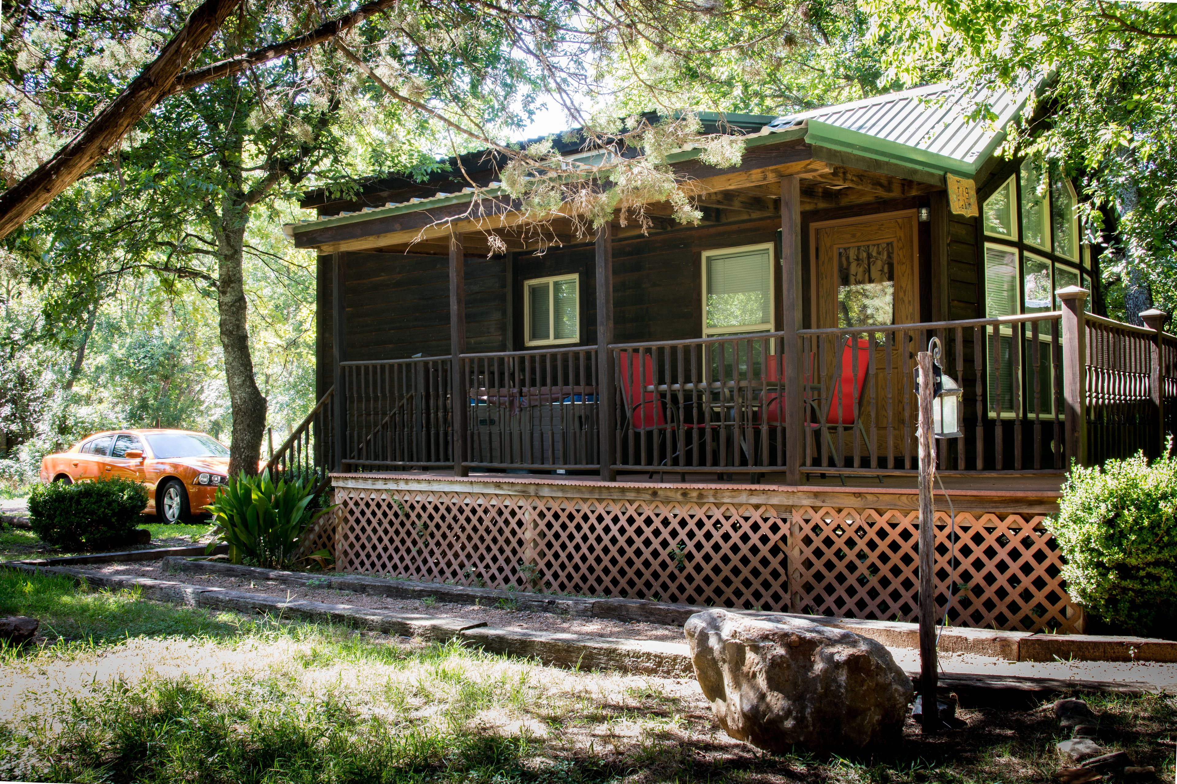 A cabin with a porch, a covered deck, and a view of the surrounding forest.