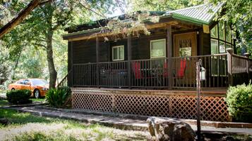 A cabin with a porch, a covered deck, and a view of the surrounding forest.