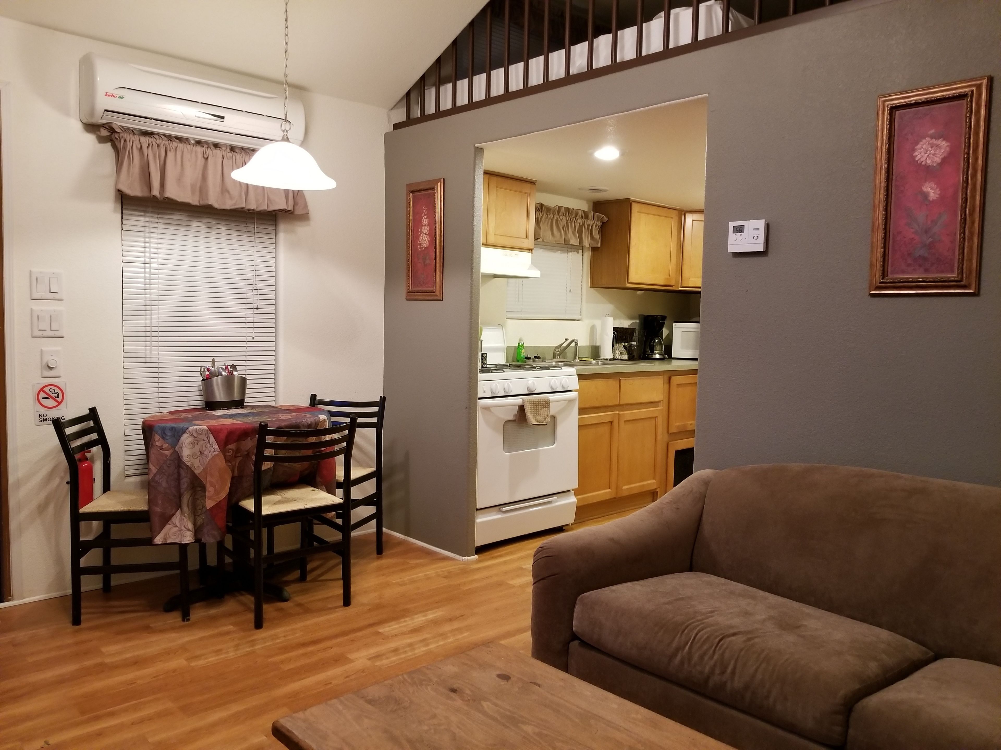 Un espace de vie compact comprenant un coin repas, une kitchenette et un canapé.
