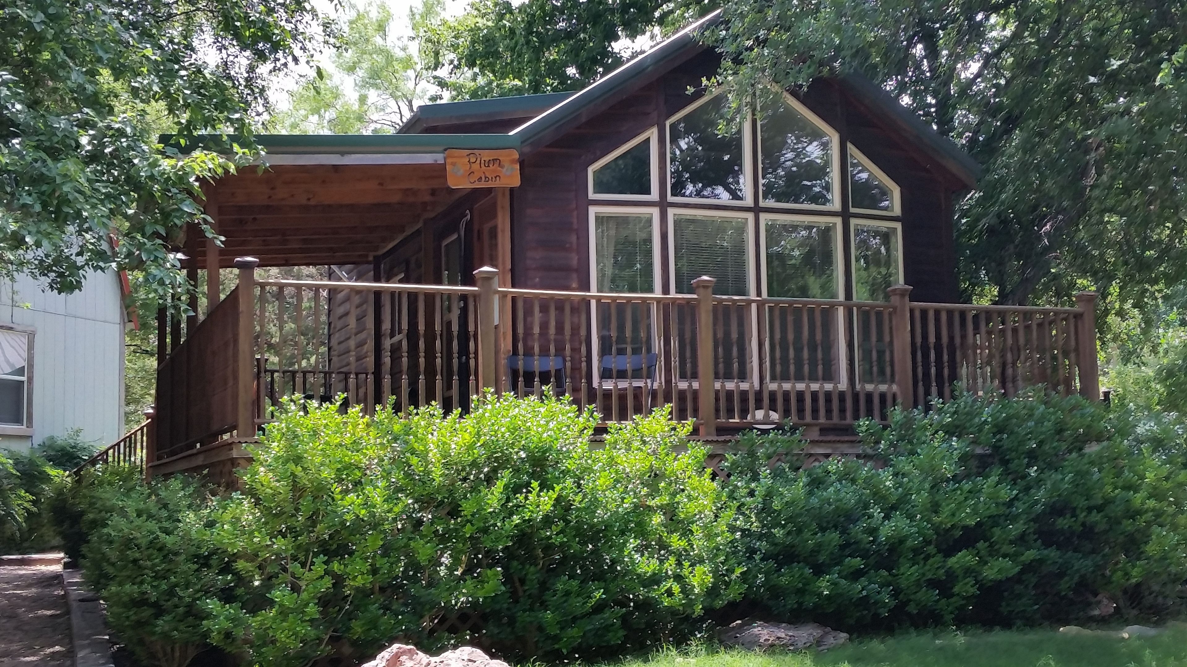 A cabin with a wooden deck, a covered porch, and a large window.