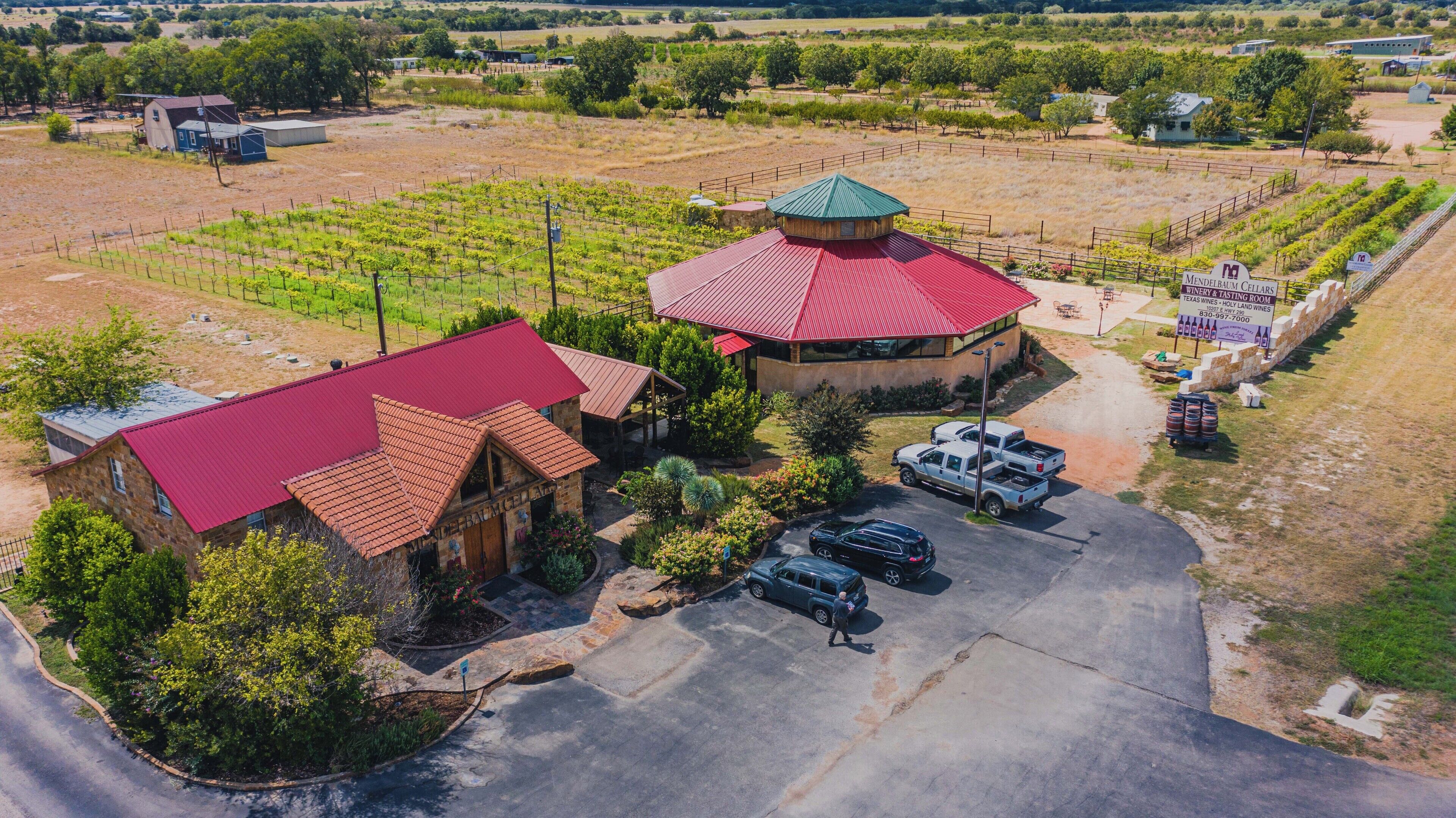 A vineyard with a tasting room and a building with a red roof.