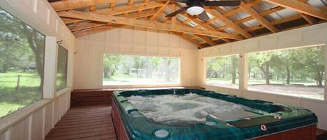 A hot tub in a covered outdoor area with wooden beams and large windows.