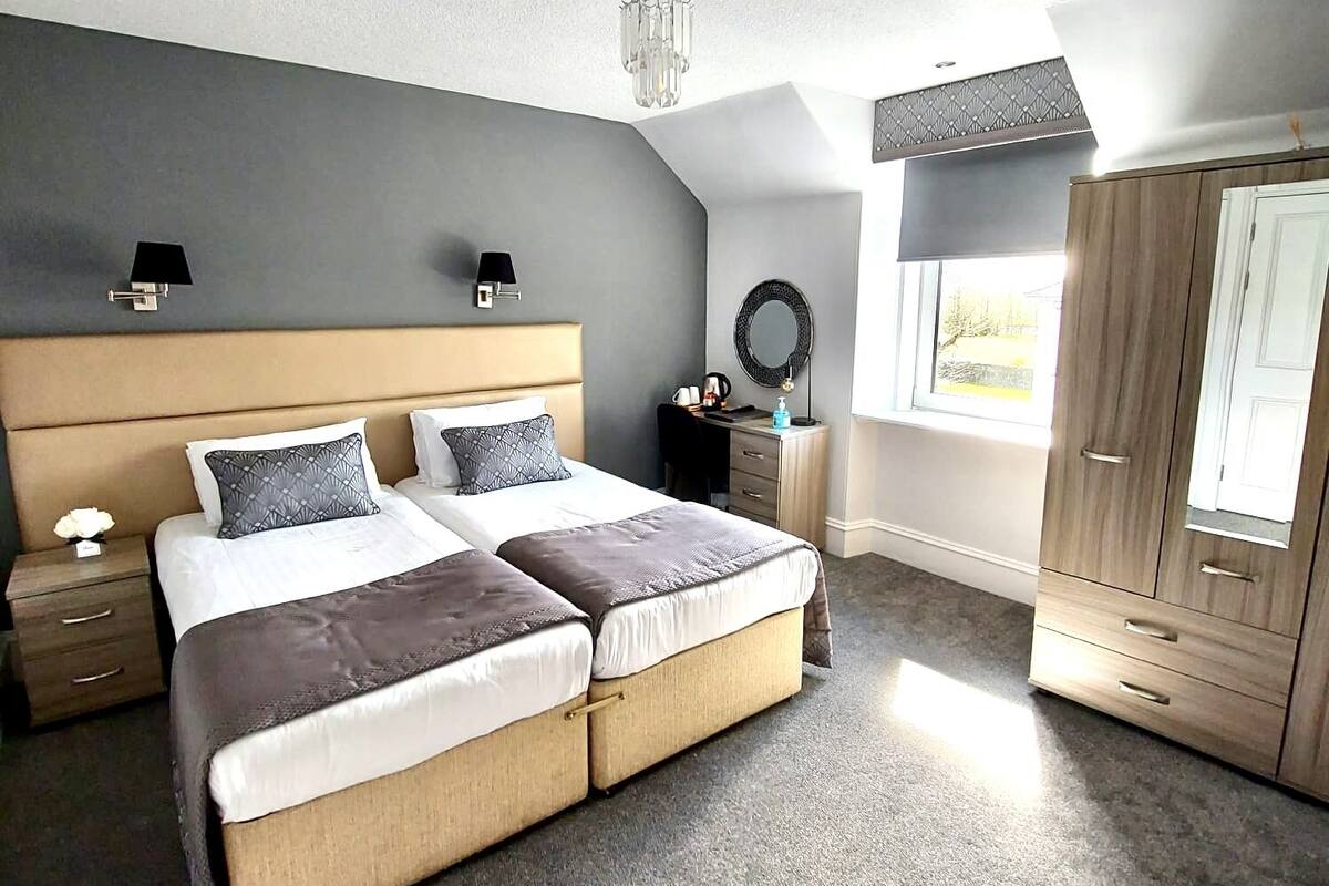 A bedroom with a large bed, a nightstand, a dresser, and a window with a view.