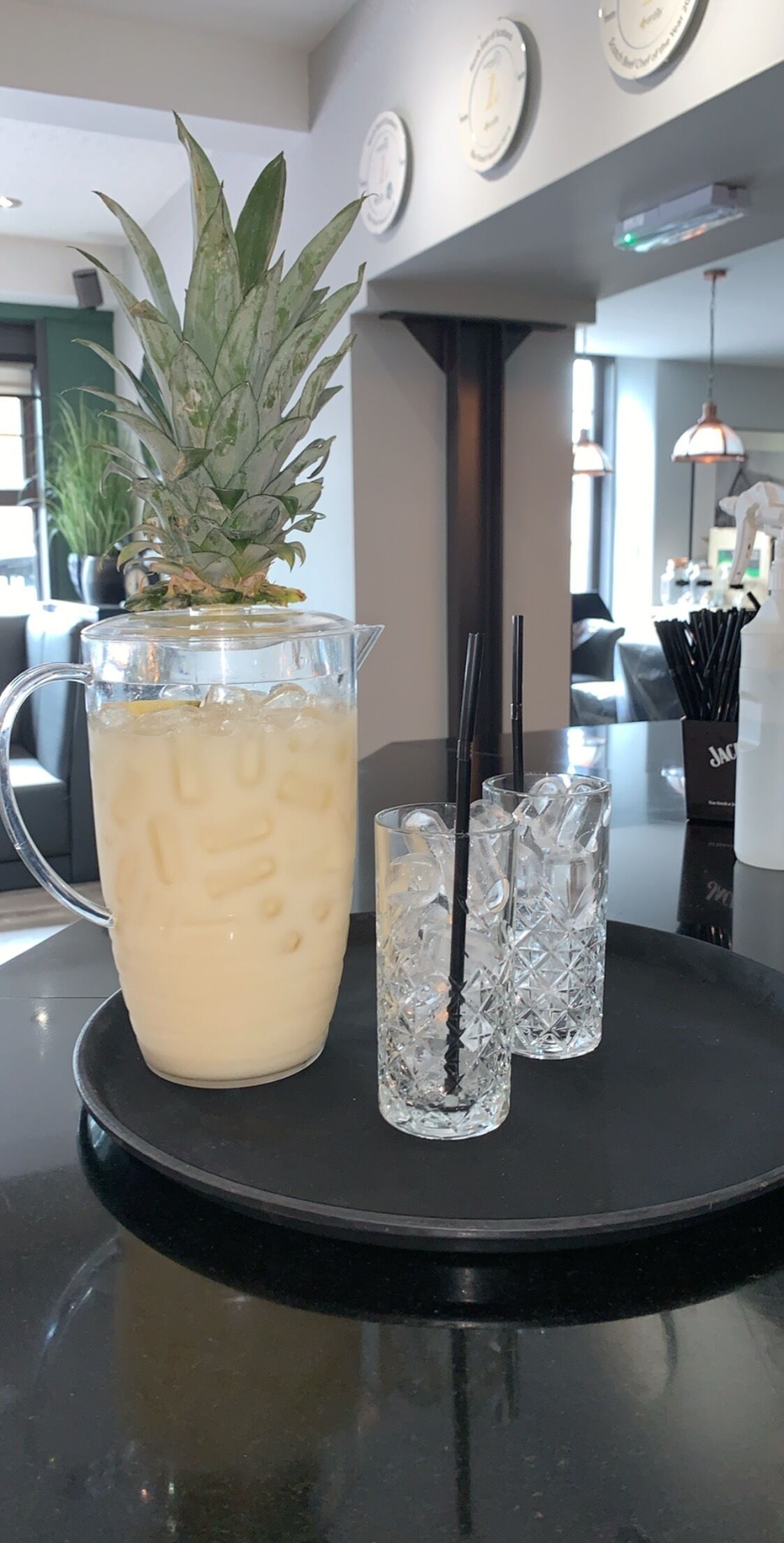 Zona de bar con una jarra de bebida fría, un vaso y una pequeña planta en maceta.