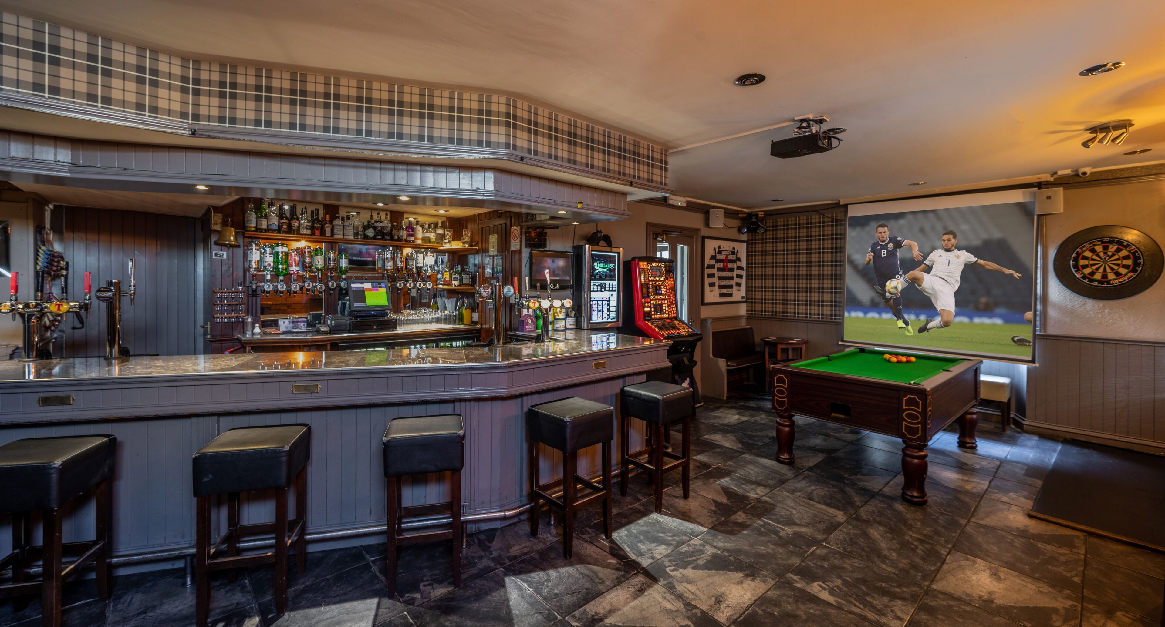 A bar area with stools, a pool table, and a dartboard.