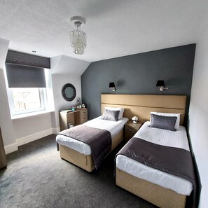 A bedroom with two beds, a window, a desk, and a chandelier. - The Newmachar Hotel (Aberdeen)