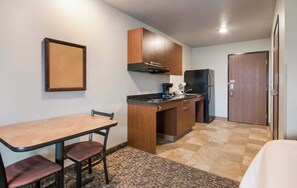 A compact kitchen with a dining table and chairs, a refrigerator, and wooden cabinets. - My Place Hotel - Nashville East-I40/Lebanon, TN (Lebanon)