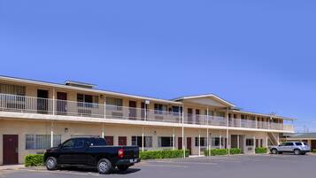 A motel with a two-story structure, a parking lot, and a black pickup truck parked in front.