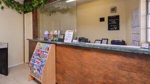 A reception desk with a wooden counter, a glass partition, and a bulletin board with a welcome sign.