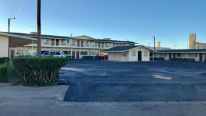 A motel with multiple units, a parking lot, and a small building in the foreground.