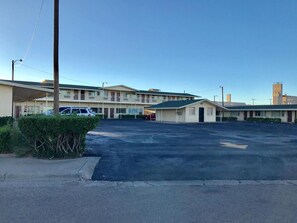 A motel with multiple units, a parking lot, and a small building in the foreground.
