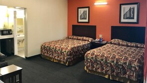 A hotel room with two beds, a desk, and a chair. There are two framed pictures on the wall.
