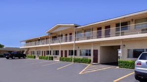 A motel with a two-story structure, a parking lot, and a covered walkway. - Scottish Inns & Suites (Lubbock)
