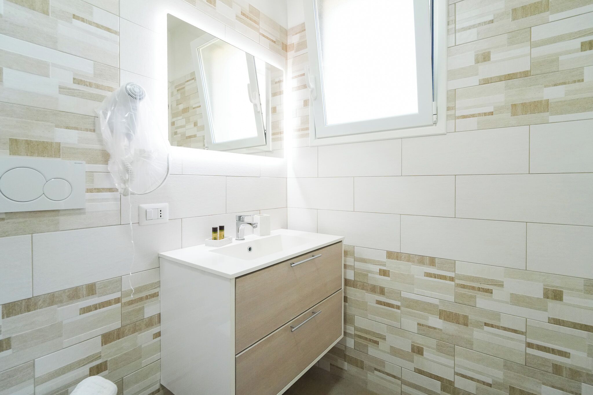 Un baño con un lavamanos blanco, un mueble de madera y un espejo encima.