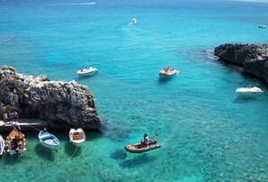 A coastal scene with several boats anchored near rocky formations. - Residence La Pineta (Otranto)