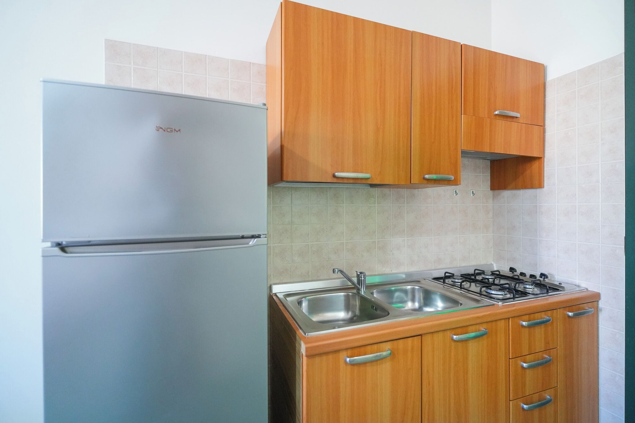 Una cocina con armarios de madera, un refrigerador de acero inoxidable y una estufa a gas.