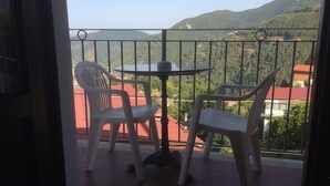A balcony with two white plastic chairs and a small round table, overlooking a mountainous landscape. - Albergo San Carlo (Massa)