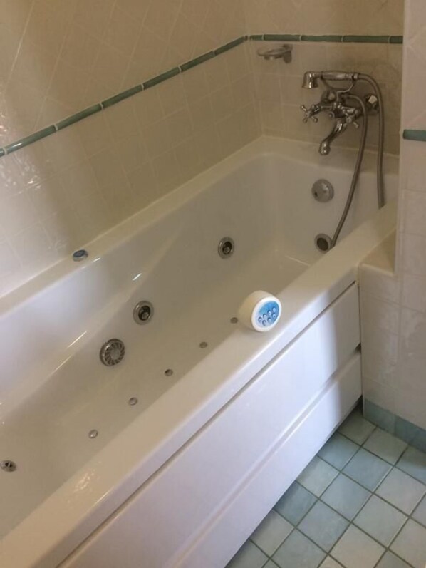 Un baño moderno con una bañera independiente, un cabezal de ducha de mano y un inodoro empotrado.