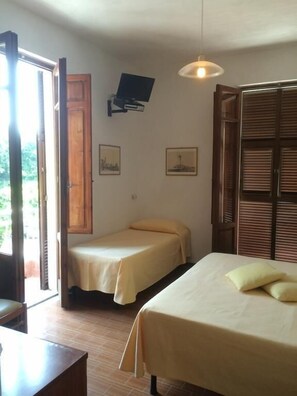 A room with two beds, a wooden door, a television mounted on the wall, and a window with blinds. - Albergo San Carlo (Massa)